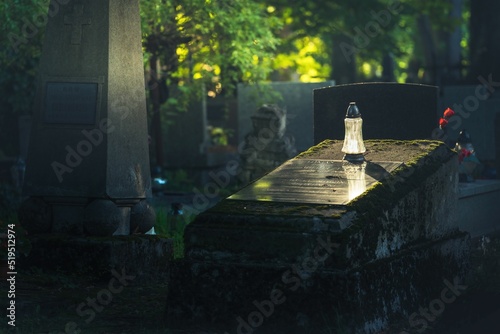 Znicz na cmentarzu postawiony na grobowcu - pada na niego słońce