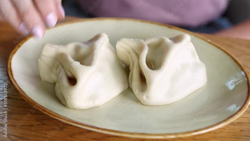 a woman's hand takes khinkali from a plate. Georgian cuisine. a woman's hand takes khinkali from a plate. Georgian cuisine.