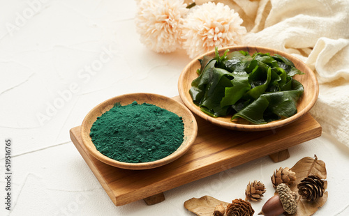 laminaria or kelp seaweed and spirulina powder in wood plate background. spirulina powder with konbu and alga food on white table background.                               photo