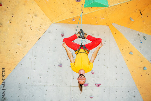 Quadro su tela A man hangs upside down in a lotus position on a climbing wall