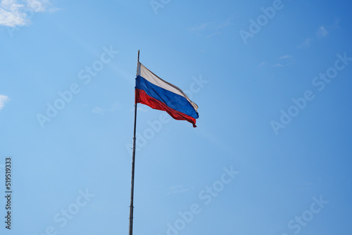 the Russian flag flies against the blue sky. 