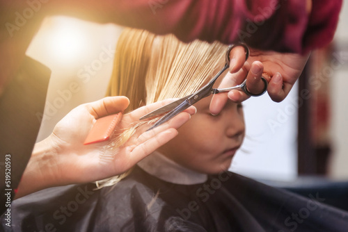 Barber woman make fashionable pretty hairstyle for cute little girl