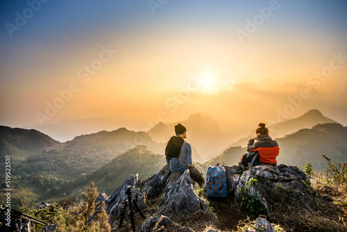 couple hiking at sunset mountain with heavy backpack golden hour for photography