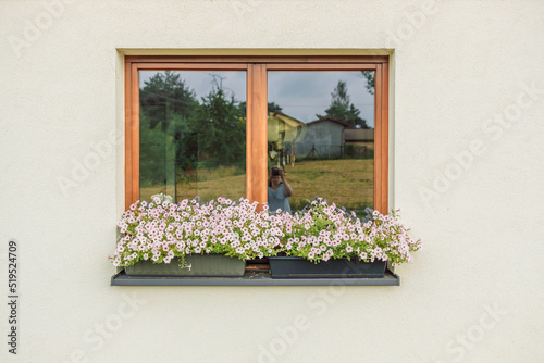 Beautiful style window and flower box with light summer flowers in Poland photo