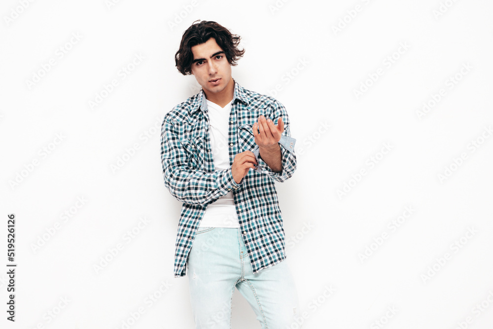 Portrait of handsome confident model. Sexy stylish man dressed in checkered shirt and jeans. Fashion hipster male posing near white wall in studio. Isolated Portrait of handsome confident model. Sexy stylish man dressed in checkered shirt and jeans. Fashion hipster male posing near white wall in studio. Isolated