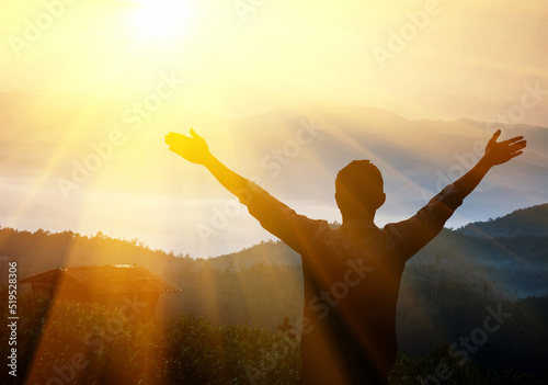Fototapeta Young man at sunset raises his hands up. Person with arms raised