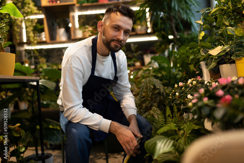 experienced male gardener surrounded by potted plants looking at the camera © Ivan Traimak
