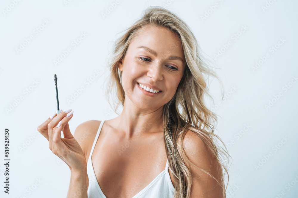 Portrait of blonde young woman with eyebrow mascara brush on white background Portrait of blonde young woman with eyebrow mascara brush on white background