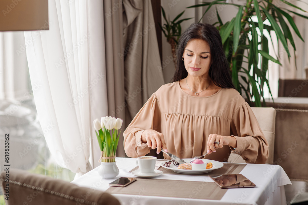 Elegant caucasian woman in dress is eating tasty sweet dessert in the cafeteria Elegant caucasian woman in dress is eating tasty sweet dessert in the cafeteria
