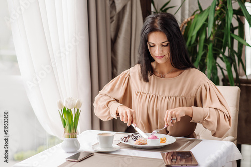 Elegant caucasian woman in dress is eating tasty sweet dessert in the cafeteria © rostyslav84