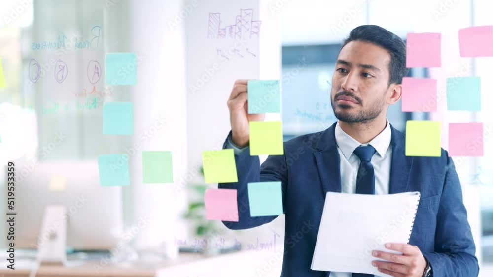 Business man thinking of ideas, planning a strategy and writing notes on a glass wall in an office. Focused expert and dedicated manager staying organized while analyzing information and solutions