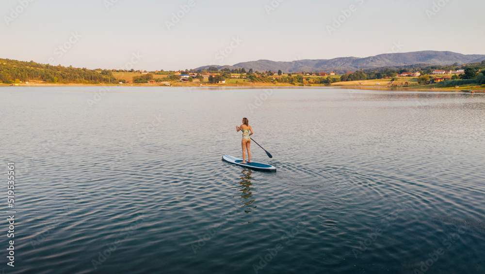 Naklejka premium Woman riding paddleboard on lake