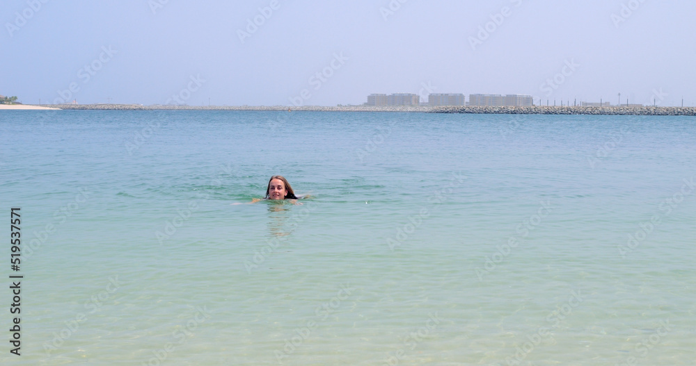 European woman in bikini swimming on Jumeirah beach, Dubai