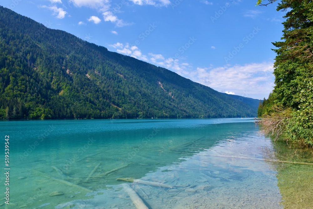 View of Weissensee lake in Carinthia or Kärnten in Austria with forest covered mountains above