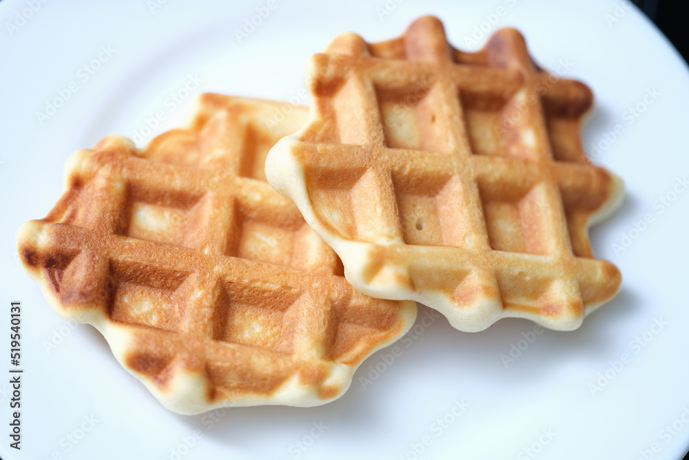 Two freshly baked Belgian waffles on white plate Two freshly baked Belgian waffles on white plate