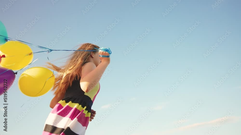 girl runs with balloons a across in the park. holiday birthday. happy family kid dream concept. girl child runs blue sky behind in fun the summer in the park holds balloons in his hand girl runs with balloons a across in the park. holiday birthday. happy family kid dream concept. girl child runs blue sky behind in fun the summer in the park holds balloons in his hand