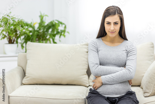 Photo of pregnant woman looking at camera and touching her stomach.