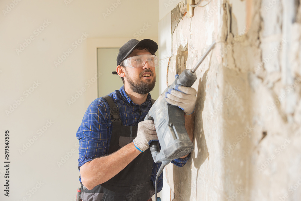Close up portrait of a man renovating an apartment a guy wearing safety glasses is cupping tiles in the kitchen bathroom with a hammer.
