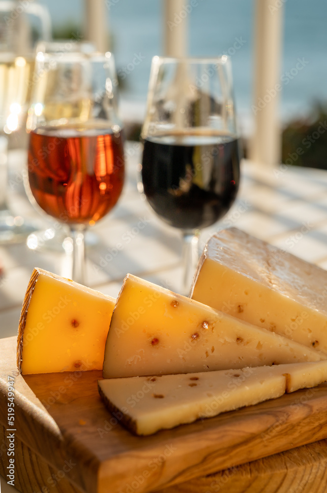 Spanish hard Andalusian cheese filled with Pedro Ximenez sweet sherry served outdoor with two glasses of sherry wine with blue sea on background