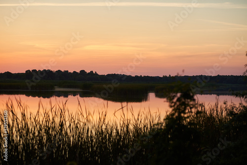 Beautiful sunset over a rural river and grass in the foreground