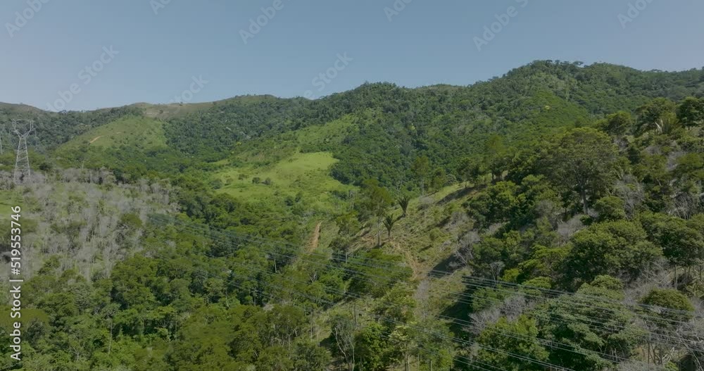 Hills with lush vegetation and overhead powerlines in sunny day. Slow aerial Hills with lush vegetation and overhead powerlines in sunny day. Slow aerial