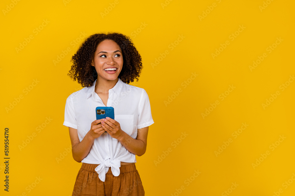 Portrait of charming minded girl hold telephone look empty space isolated on yellow color background Portrait of charming minded girl hold telephone look empty space isolated on yellow color background