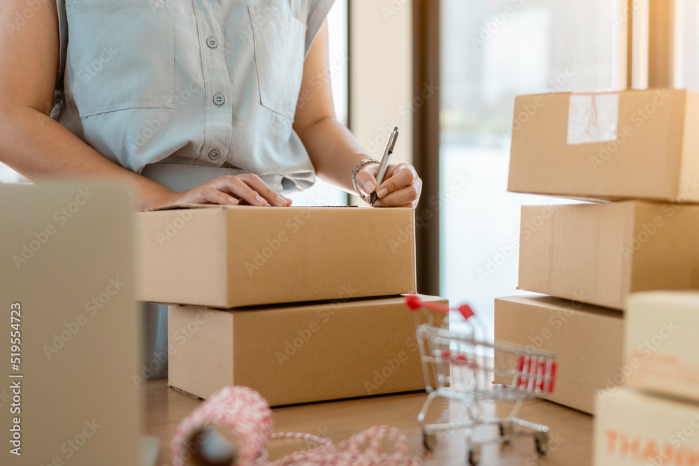 Close up online business owner prepares product for delivery to the customer. Online entrepreneur writing address on parcel box for delivery to customer. small business owner, SME concept. Close up online business owner prepares product for delivery to the customer. Online entrepreneur writing address on parcel box for delivery to customer. small business owner, SME concept.