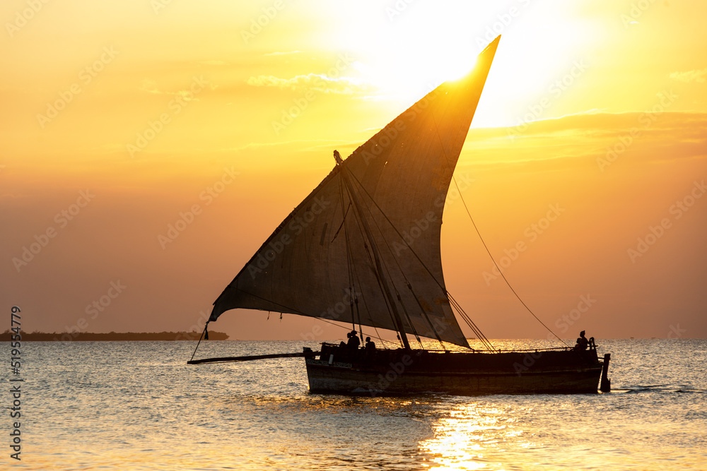 traditional sailing dhow heading out to sea at dusk on a calm evening ocean