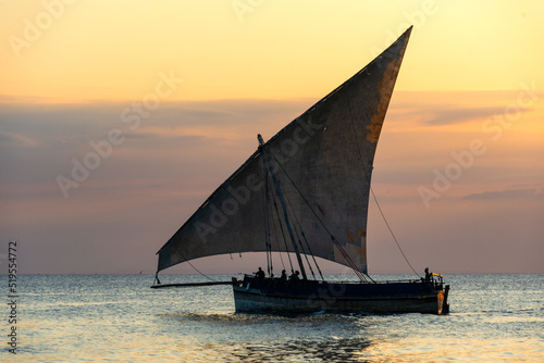 traditional sailing dhow heading out to sea at dusk on a calm evening ocean