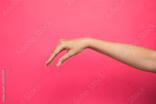 Empty female hand pretending holding something, isolated on pink background
