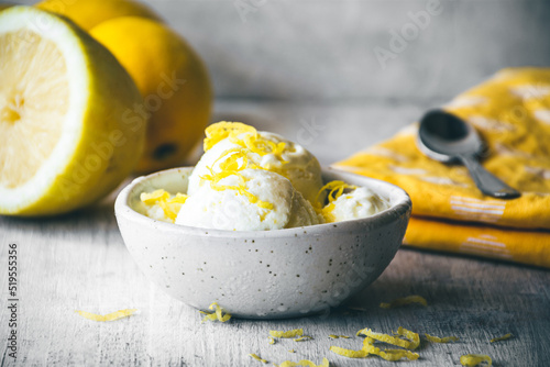 cuenco con helado de limón sobre una mesa de madera blanca, con limones detrás Fototapet