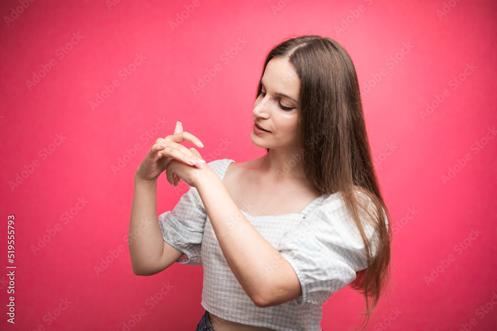 Young woman applying hand cream on pink background Young woman applying hand cream on pink background