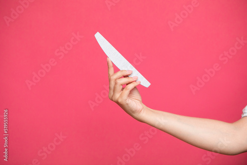 manicure and pedicure nail file in a hand isolated on pink background. cosmetic tool