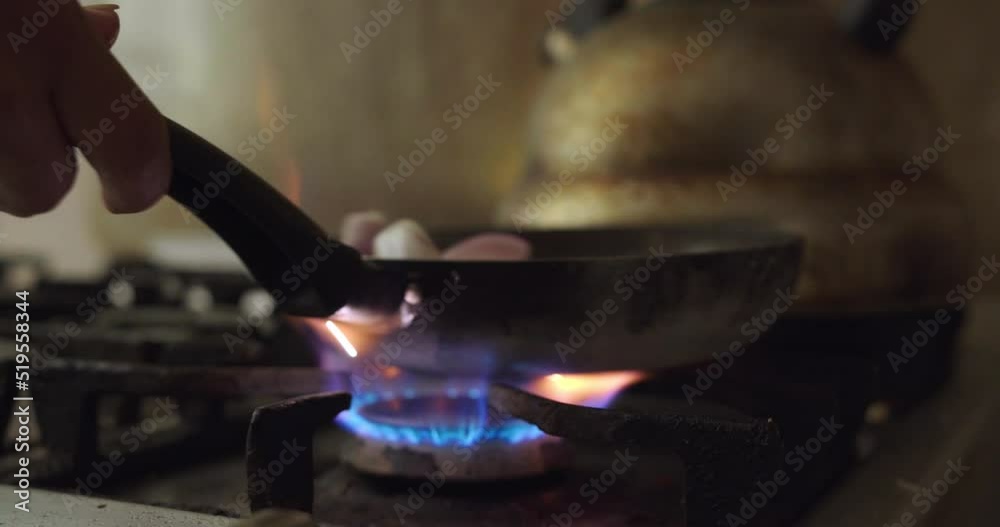 Primer plano de llama de fuego calentando sartén en cocina de casa friendo cebolla.