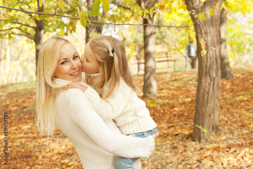 Cute happy daughter kissing her mother in cheek