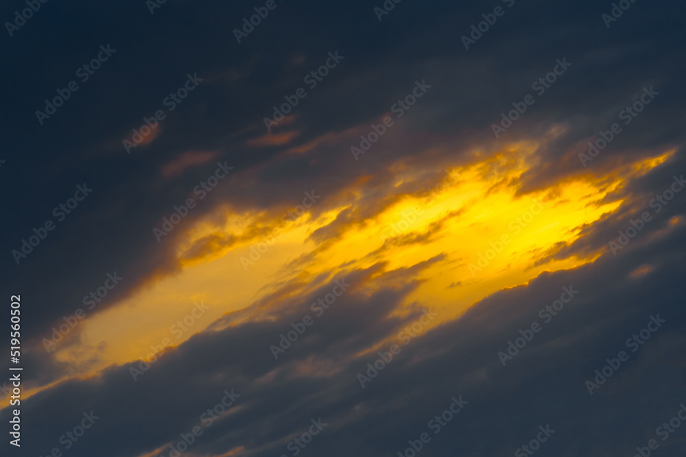 Light spot orange sunset through dark rain clouds storm beam light sky weather background
