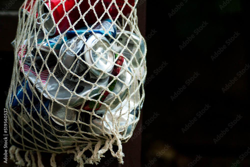 Drink cans crumpled and folded into a rag net for disposal Drink cans crumpled and folded into a rag net for disposal