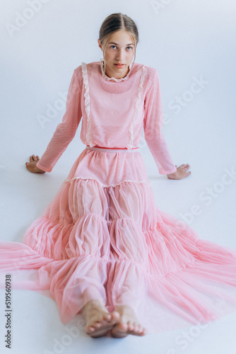 Young beauty joyful blondie girl model in pink fashion dress posing in studio on white background