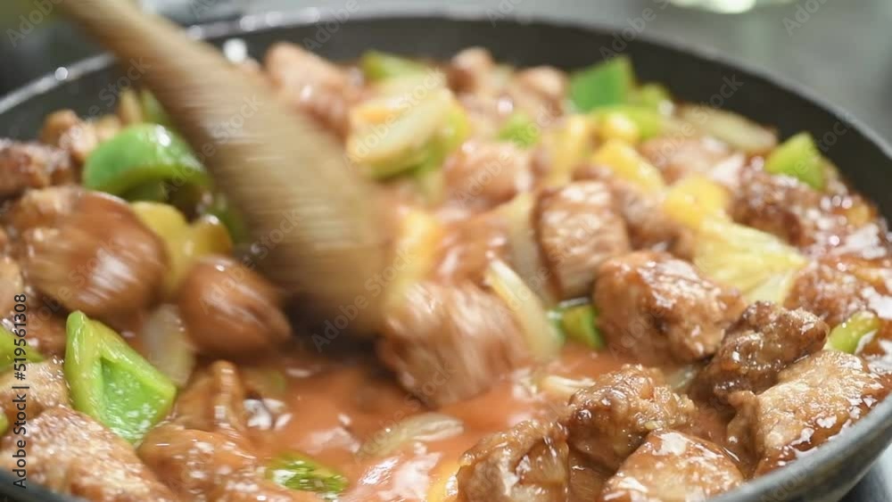 Preparing sweet and sour pork in a frying pan.

