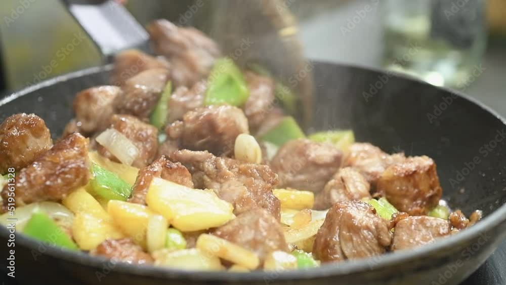 Cooking and stirring sweet and sour pork in a frying pan.
Cooking and stirring sweet and sour pork in a frying pan.