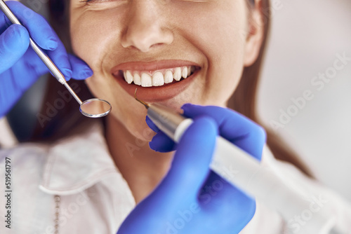 Fototapeta Naklejka Na Ścianę i Meble -  confident doctor is making ultrasonic tooth stone cleaning in modern dental cabinet