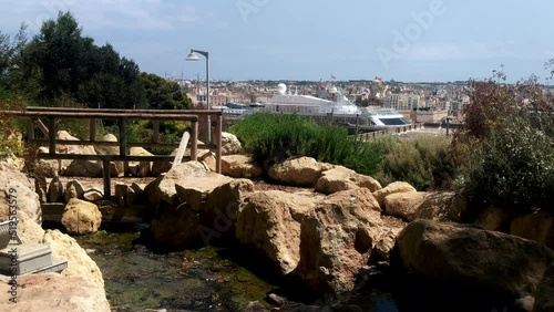 Peaceful river fountain in Herbert Ganado park in Floriana, Malta with large cruise ship and the three cities in background photo