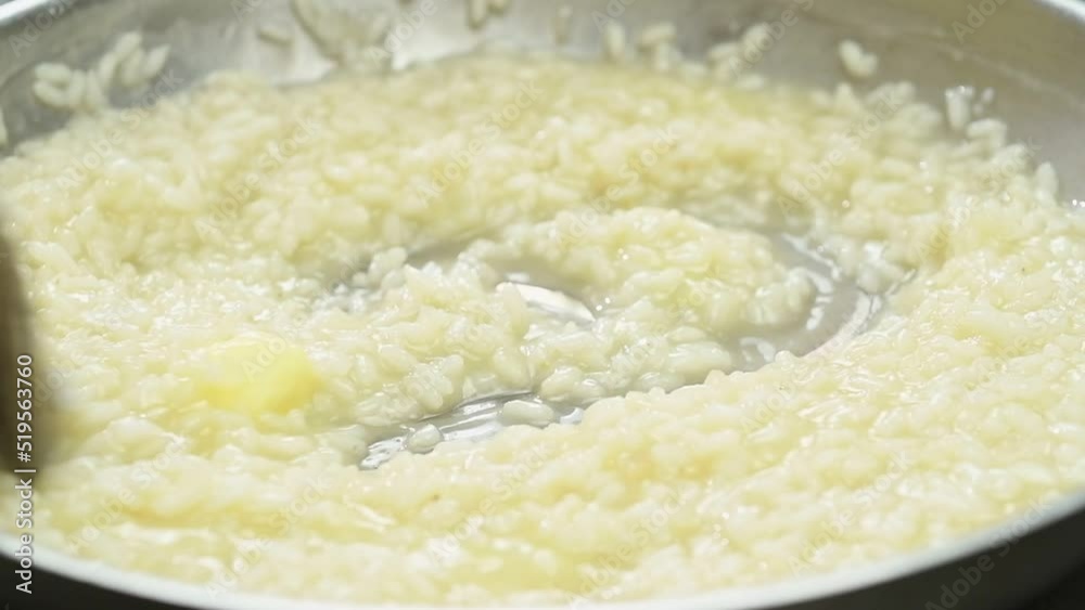 Cooking and stirring risotto in a frying pan.
Cooking and stirring risotto in a frying pan.