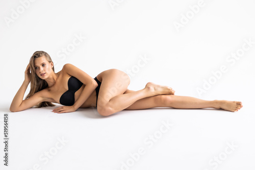 Young woman in black underwear laying down on the white background