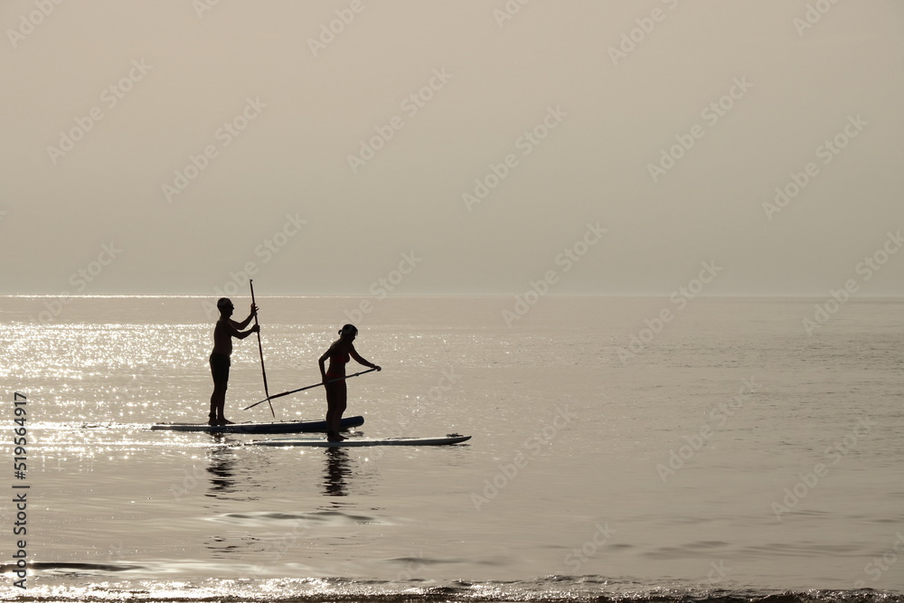 Naklejka premium Un uomo ed una donna remano vicino ad una spiaggia durante il tramonto