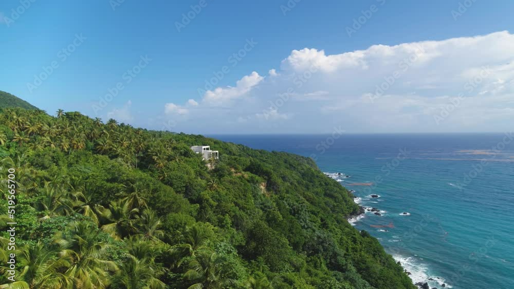 Exotic green island in the blue ocean. White villa in the palm jungle. Sea waves near the rocky coast. Travel and recreation in the tropics. Landscape of the sea on a summer sunny day. Exotic green island in the blue ocean. White villa in the palm jungle. Sea waves near the rocky coast. Travel and recreation in the tropics. Landscape of the sea on a summer sunny day.