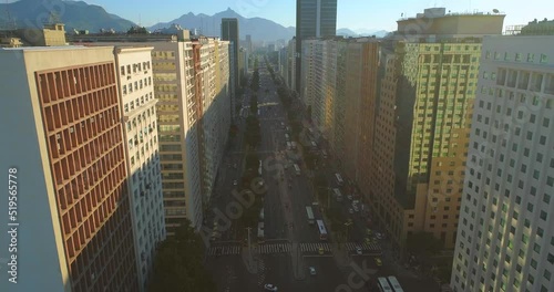 Descending aerial pulling back along the President Vargas Avenue - lined on either side by skyscrapers with mountains and blue skies in the background traffic passing below photo