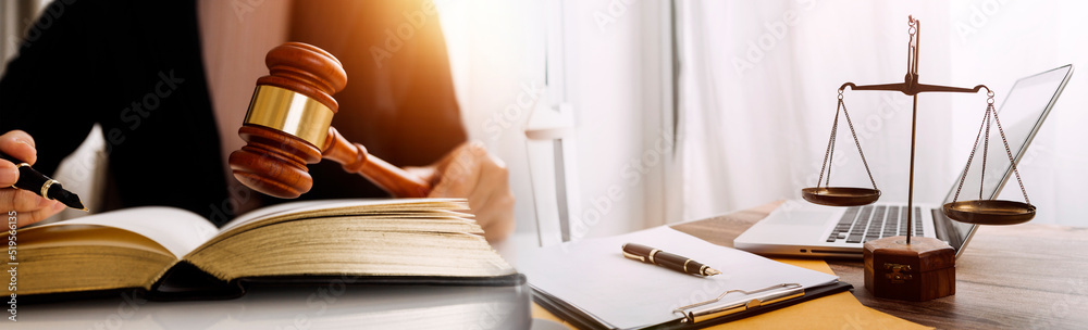 Justice and law concept.Male judge in a courtroom with the gavel, working with, computer and docking keyboard, eyeglasses, on table in morning light Justice and law concept.Male judge in a courtroom with the gavel, working with, computer and docking keyboard, eyeglasses, on table in morning light