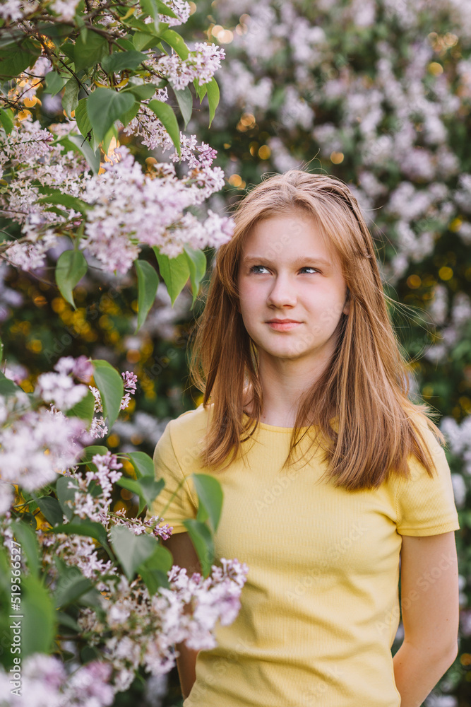 teenage girl with blond hair enjoys nature. The girl is wearing a yellow summer dress.