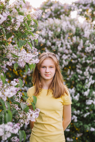 teenage girl with blond hair enjoys nature. The girl is wearing a yellow summer dress.
